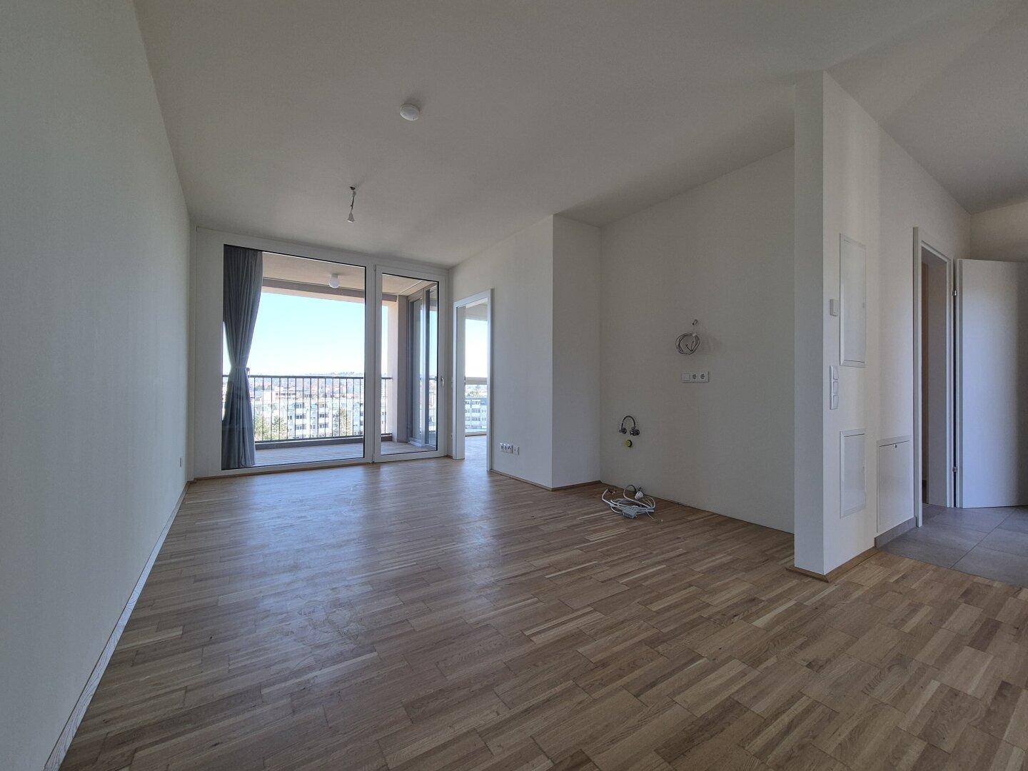 Geräumiger, heller Wohnbereich mit Parkettboden und Zugang zu einem Balkon.