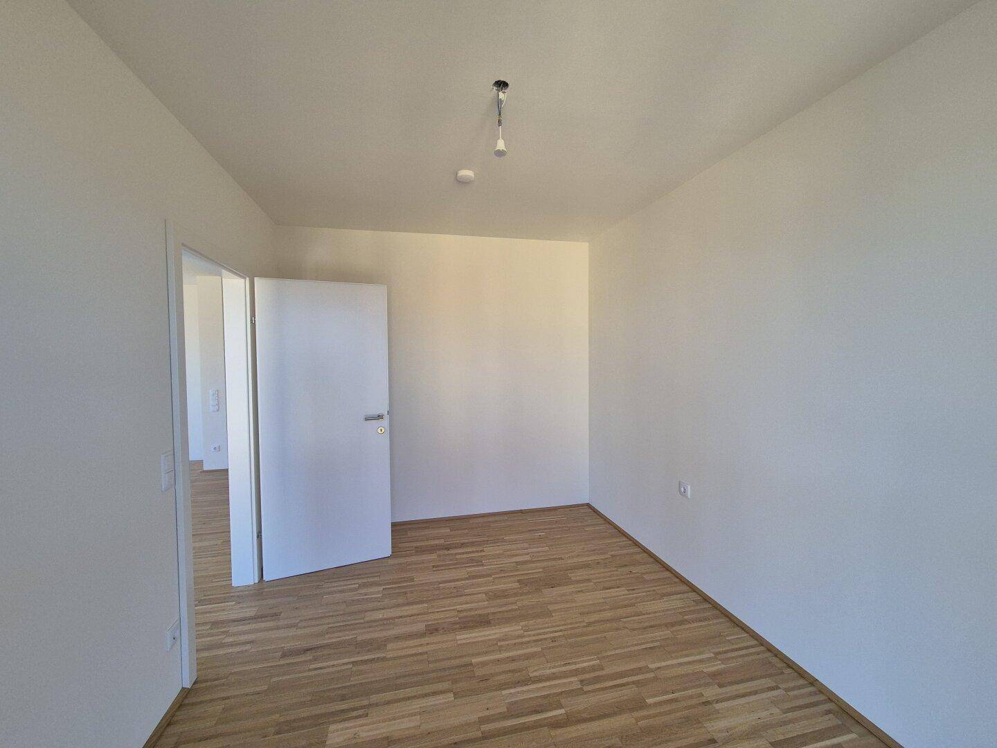 Geräumiges Zimmer mit Parkettboden und weißen Wänden, vielseitig nutzbar als Schlaf- oder Arbeitszimmer.