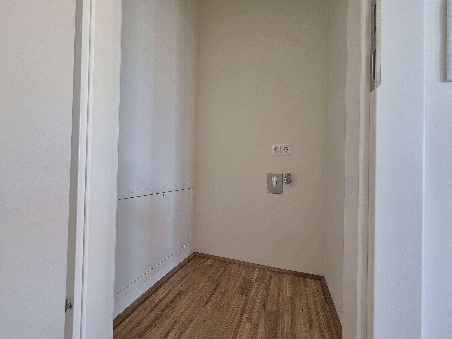 Praktischer Hauswirtschaftsraum mit Parkettboden und Anschlüssen für Waschmaschine und Trockner.