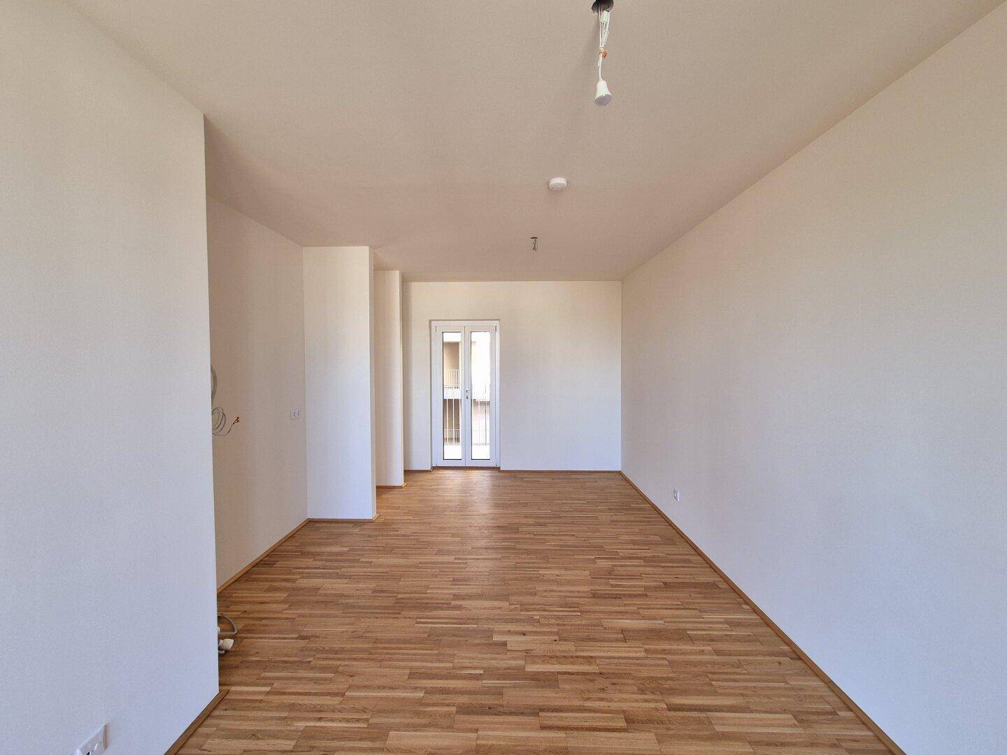Heller, leerer Raum mit Parkettboden und weißen Wänden, bereit zur individuellen Gestaltung.