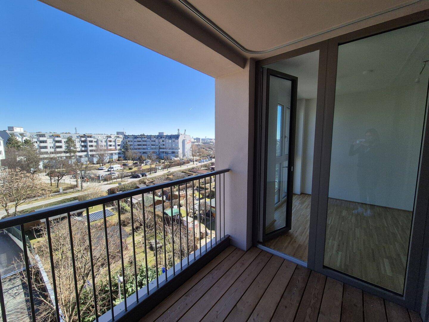 Geräumiger Balkon mit Holzboden und weitem Blick über die Nachbarschaft und Gärten.