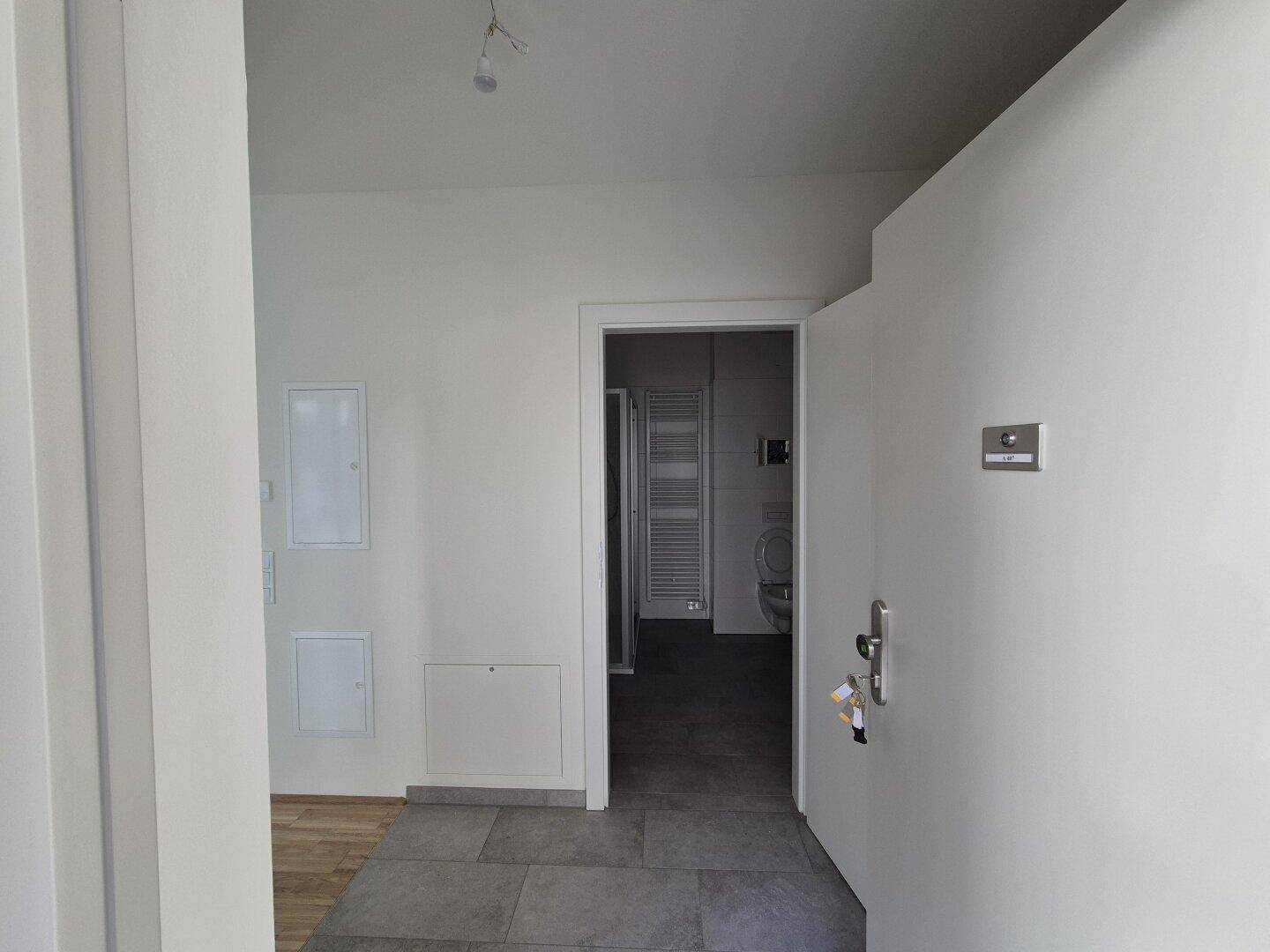 Eingangsbereich mit Fliesenboden, der zum Badezimmer und den Wohnräumen führt.