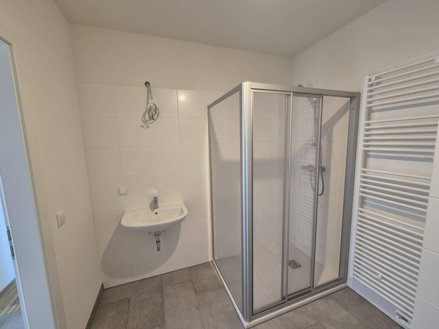 Modernes Badezimmer mit Duschkabine, Einzelwaschbecken und Handtuchheizkörper.