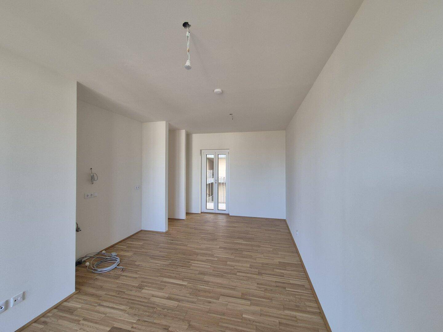 Heller, unmöblierter Raum mit Parkettboden und weiß gestrichenen Wänden, bereit zum Einzug.