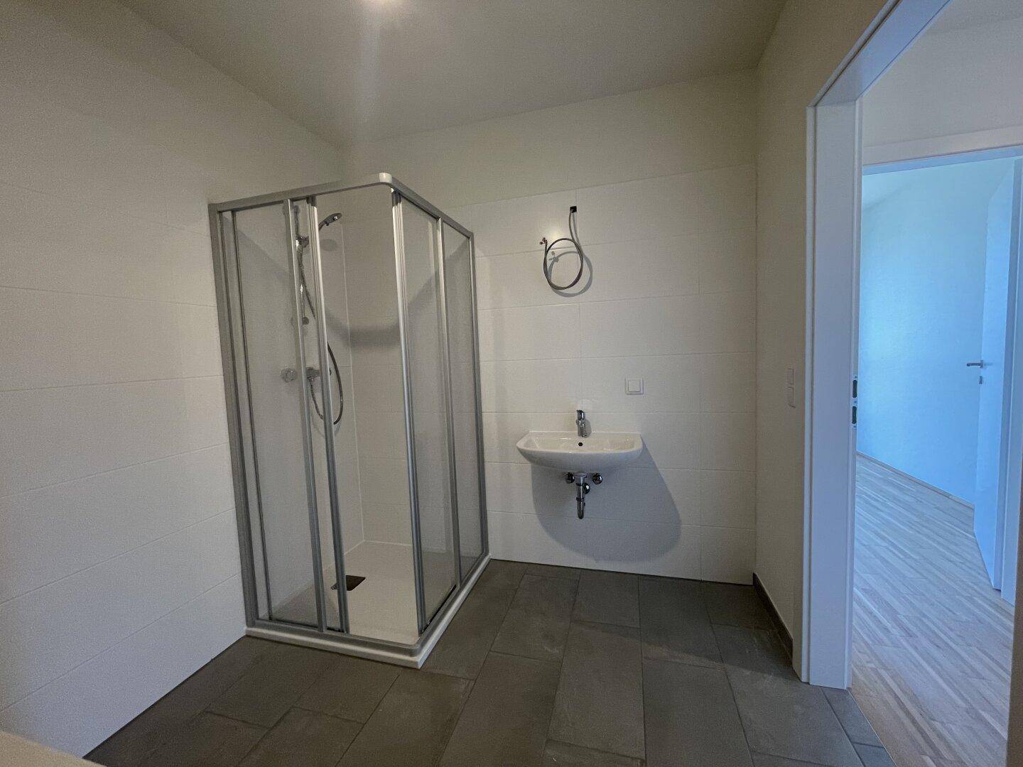 Modernes Badezimmer mit Duschkabine und Waschbecken, bereit für die Endmontage.