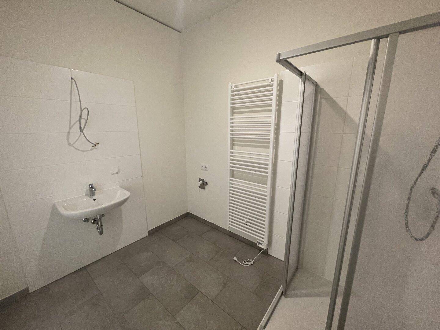Modernes Badezimmer mit Dusche, Waschbecken und beheiztem Handtuchhalter in neutralen Farben.