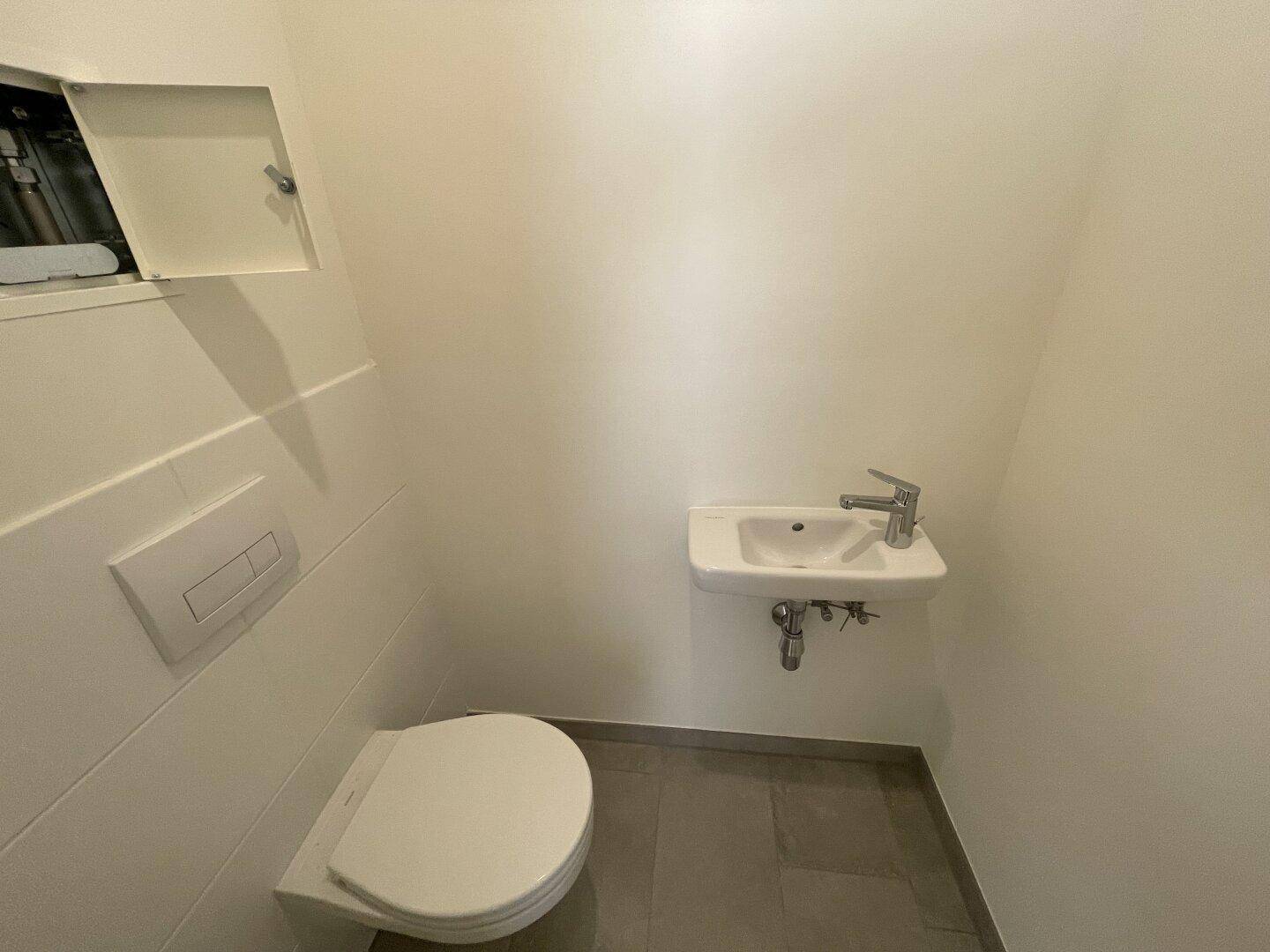 Kleines Gäste-WC mit wandhängender Toilette und kompaktem Waschbecken in hellem Design.