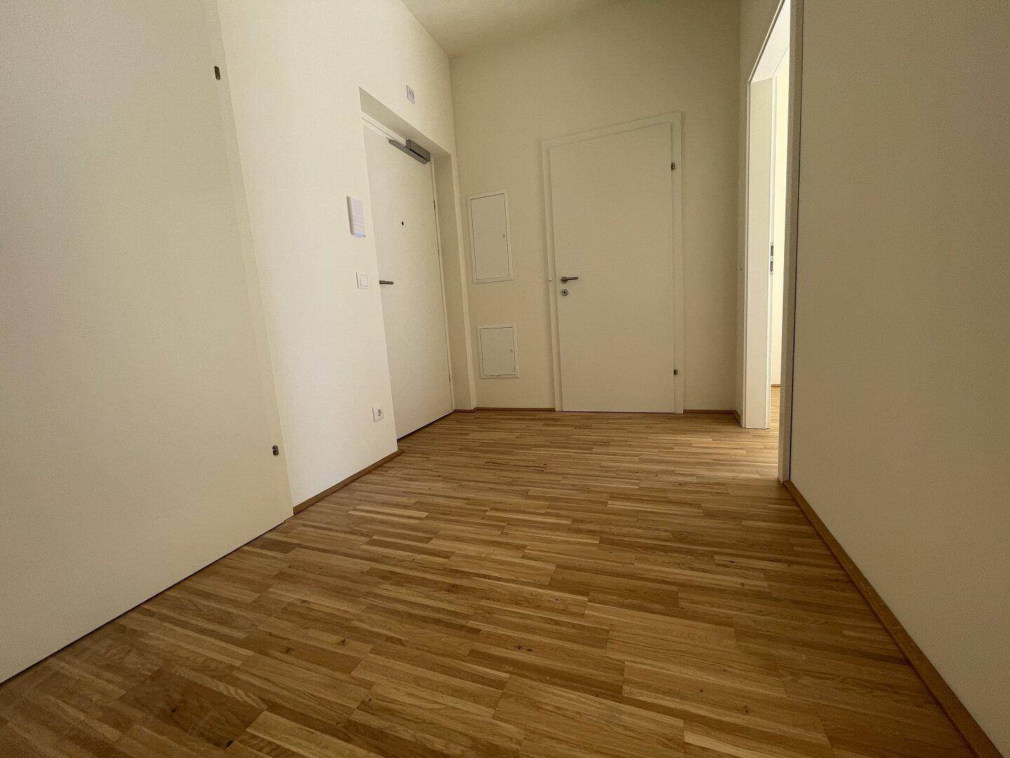 Heller Flur mit Holzboden und mehreren Türen, der verschiedene Räume verbindet.