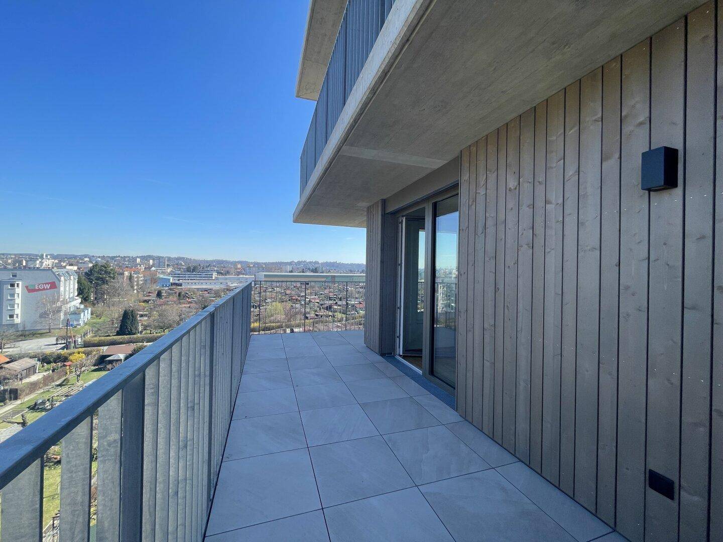 Großer Balkon mit Fliesenboden und Holzverkleidung, bietet einen weiten Blick über die Umgebung.