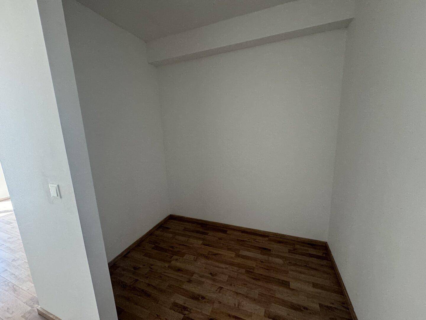 Kleiner, leerer Abstellraum mit Laminatboden und weißen Wänden, ideal für zusätzlichen Stauraum.