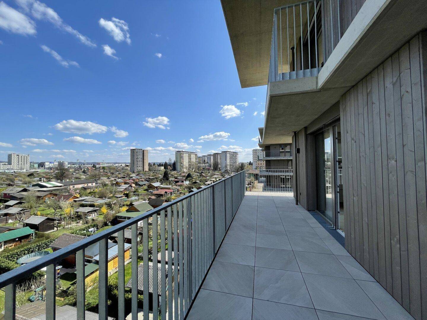 Langer Balkon mit Fliesenboden und weitem Blick über die Kleingartenanlage.