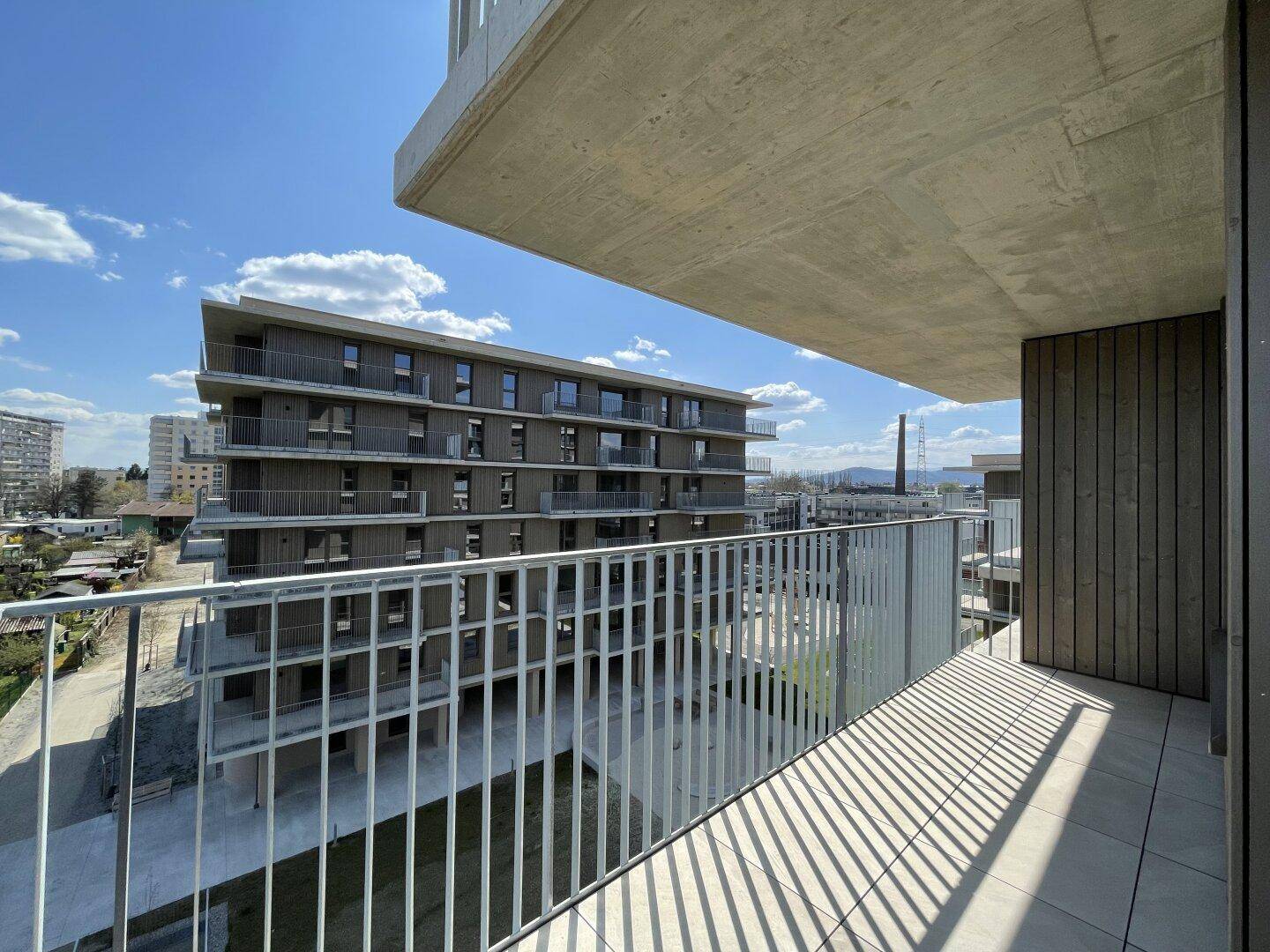 Balkon mit Blick auf ein modernes Gebäude mit Holzfassade und weitere Balkone.