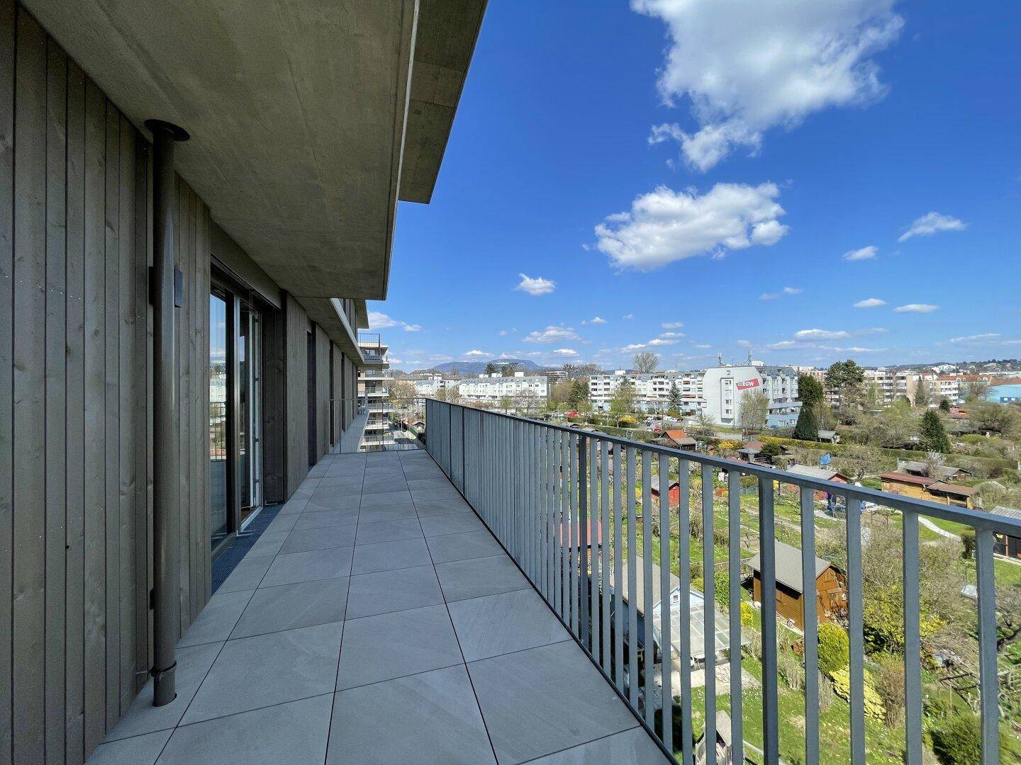 Geräumiger Balkon mit Fliesenboden und weitem Blick über die grüne Umgebung.
