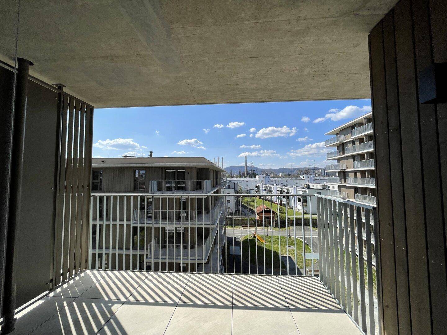 Geräumiger Balkon mit Fliesenboden und Metallgeländer, bietet einen Panoramablick auf die Stadt.