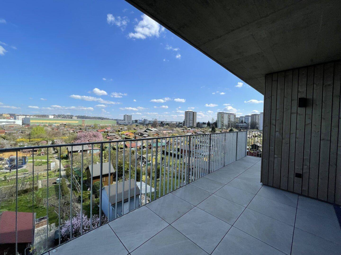 Heller Balkon mit weitem Blick über die grünen Kleingärten und die städtische Umgebung.