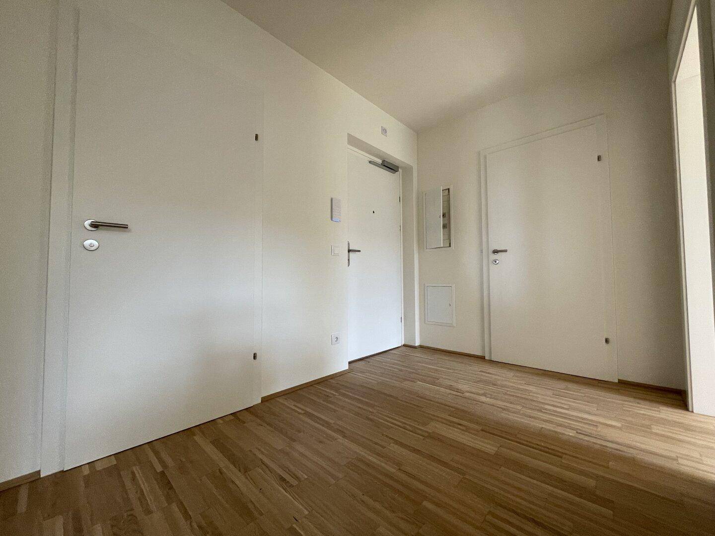 Heller Flur mit Holzboden und mehreren weißen Türen, die zu den verschiedenen Räumen führen.