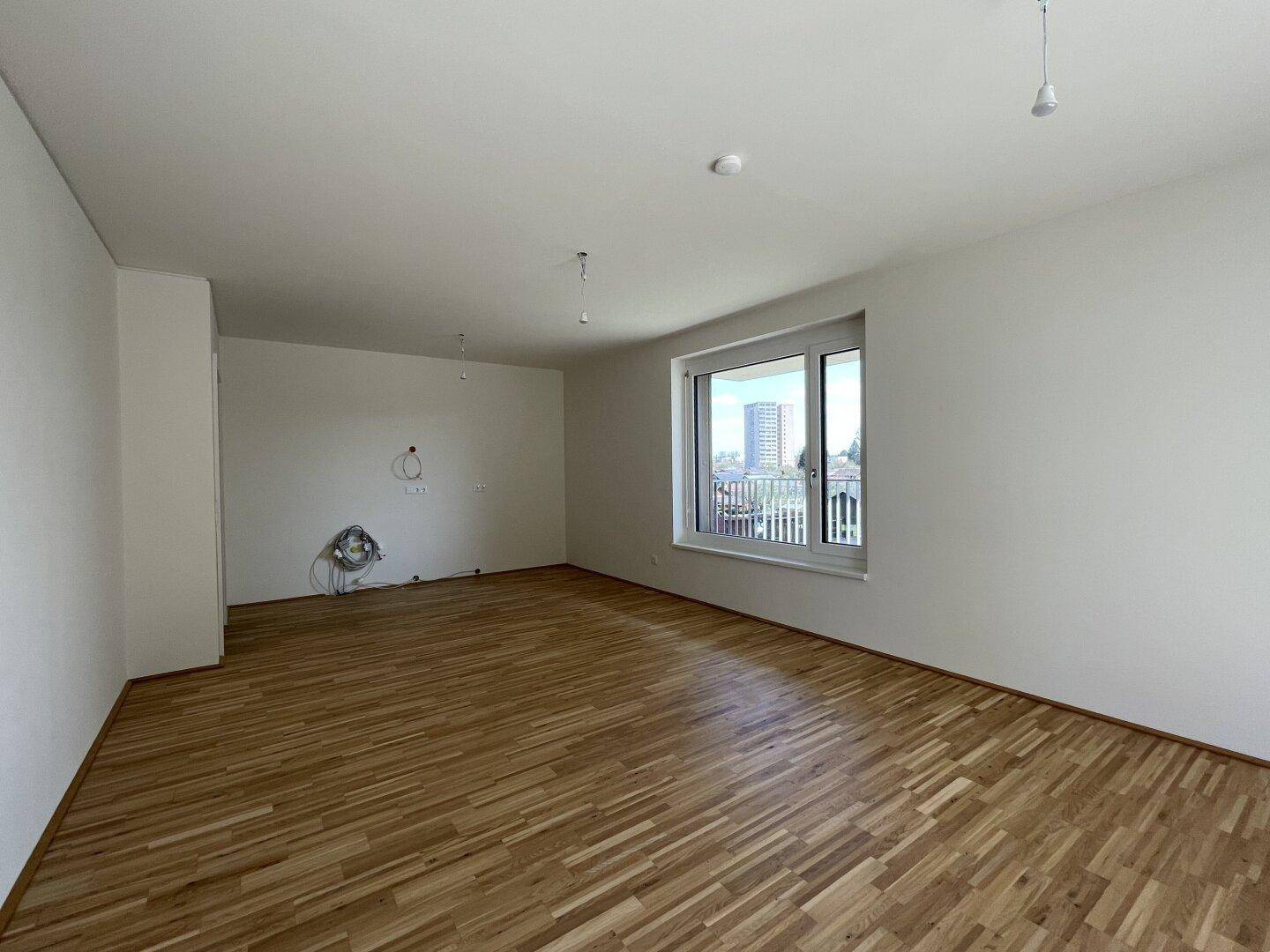 Geräumiges, helles Zimmer mit Parkettboden und großem Fenster mit Stadtblick.