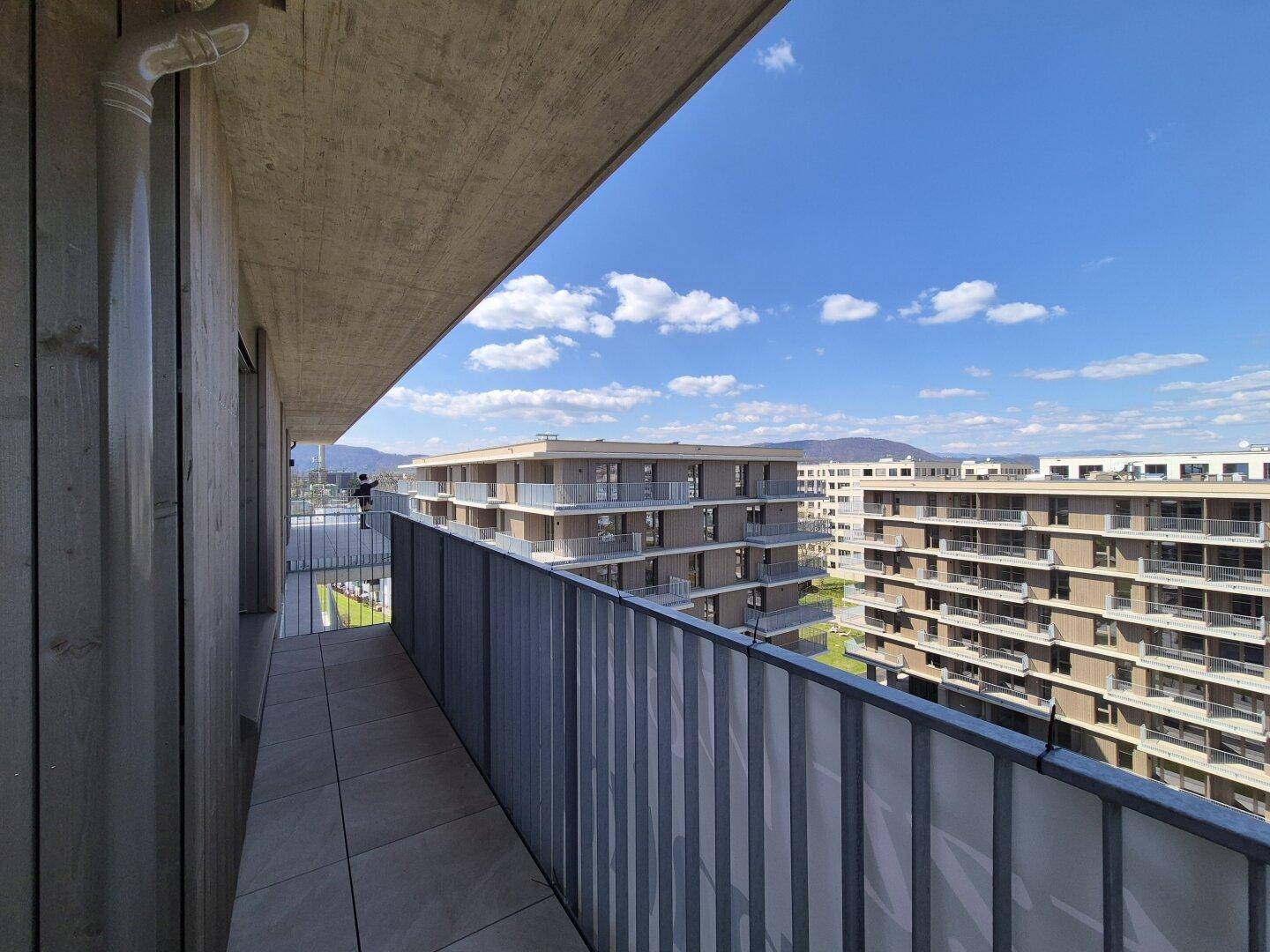 Heller Balkon mit Blick auf moderne Wohngebäude und die umliegende Landschaft.