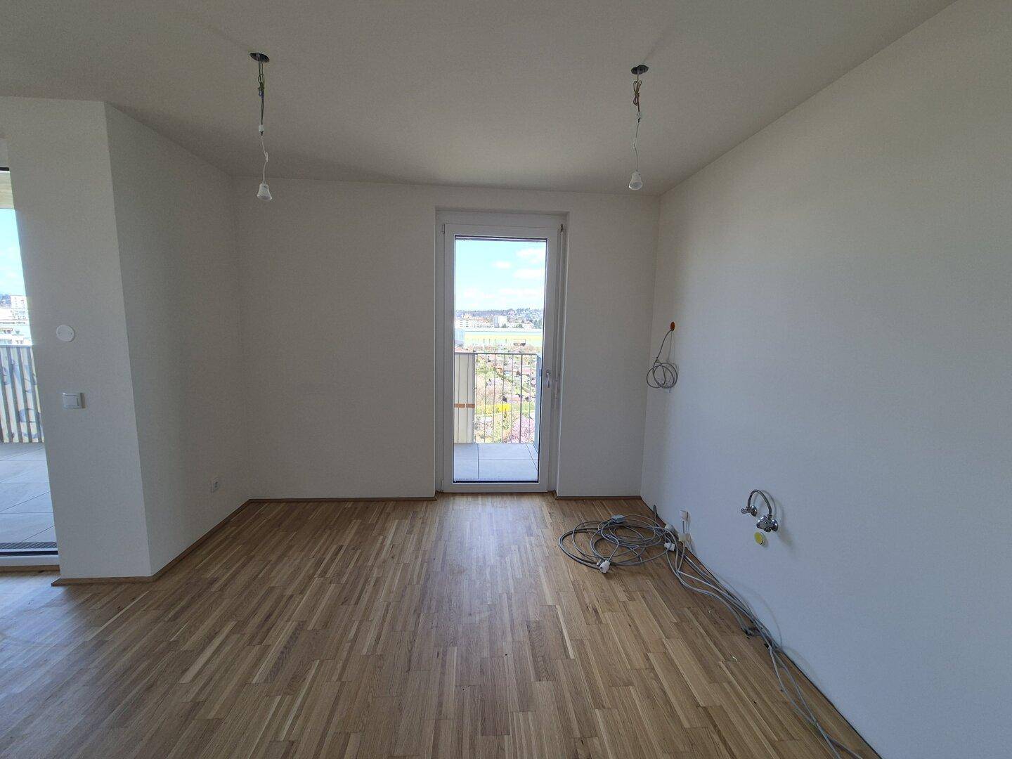 Helles Zimmer mit Parkettboden und Zugang zu einem französischen Balkon.