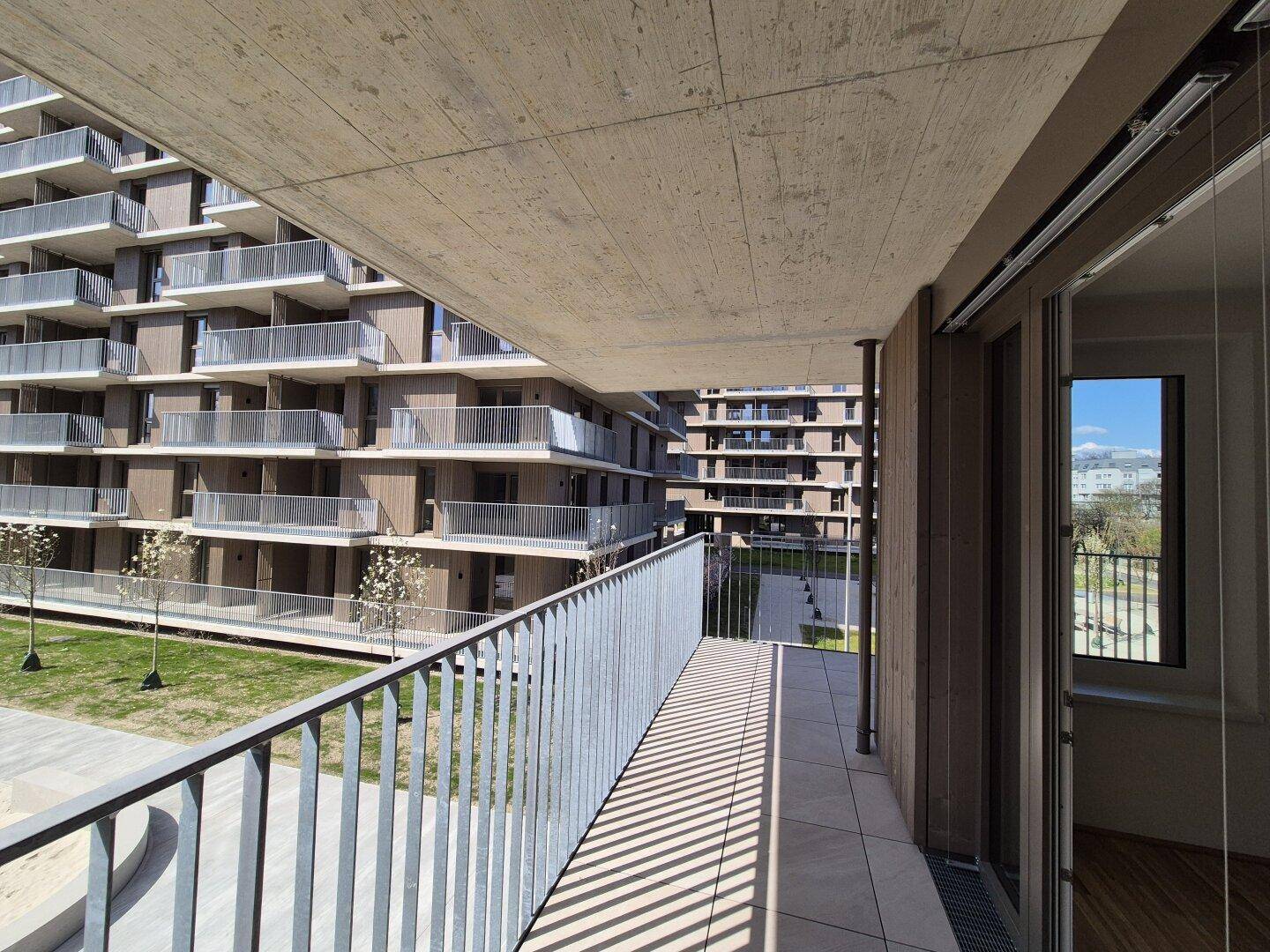 Geräumiger Balkon mit Blick auf den Innenhof und die modernen Wohngebäude.