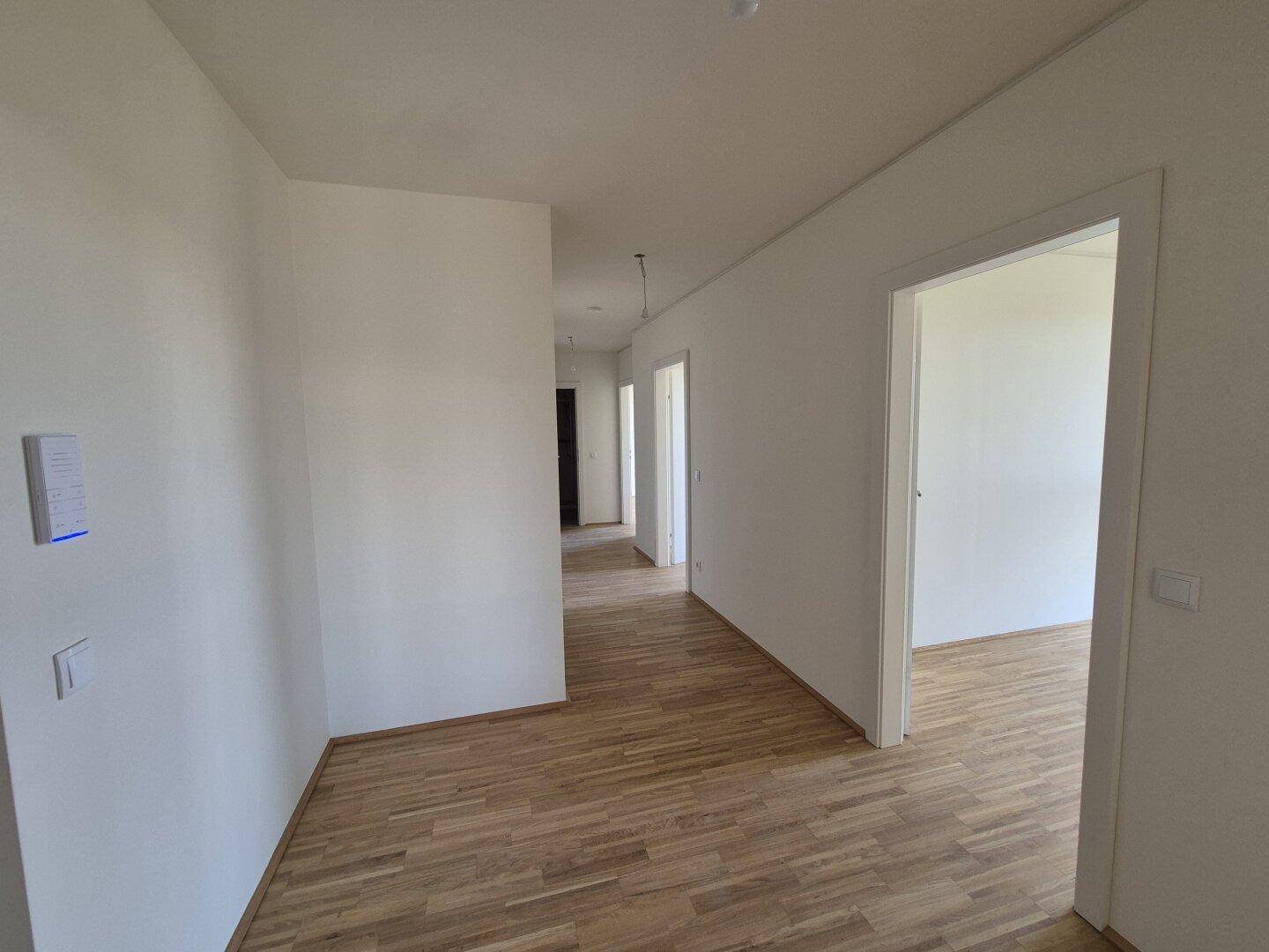 Heller Flur mit Parkettboden, der zu verschiedenen Zimmern der Wohnung führt.