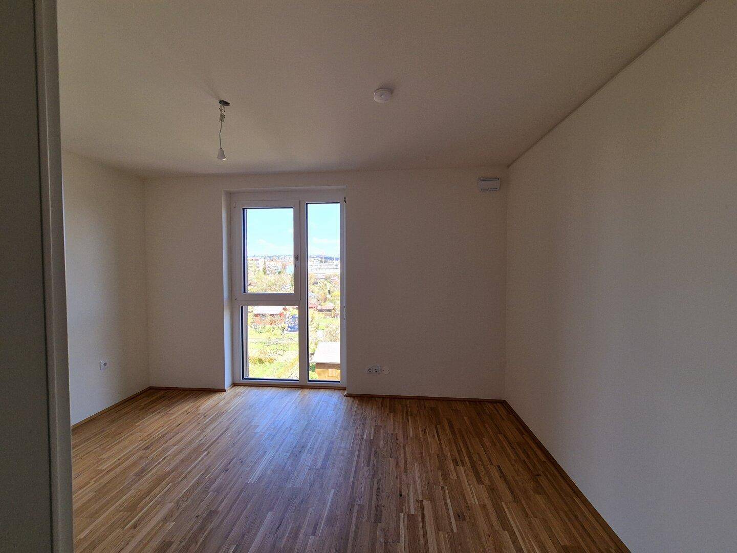 Geräumiges Schlafzimmer mit Parkettboden und großen Fenstern, die den Raum lichtdurchfluten.