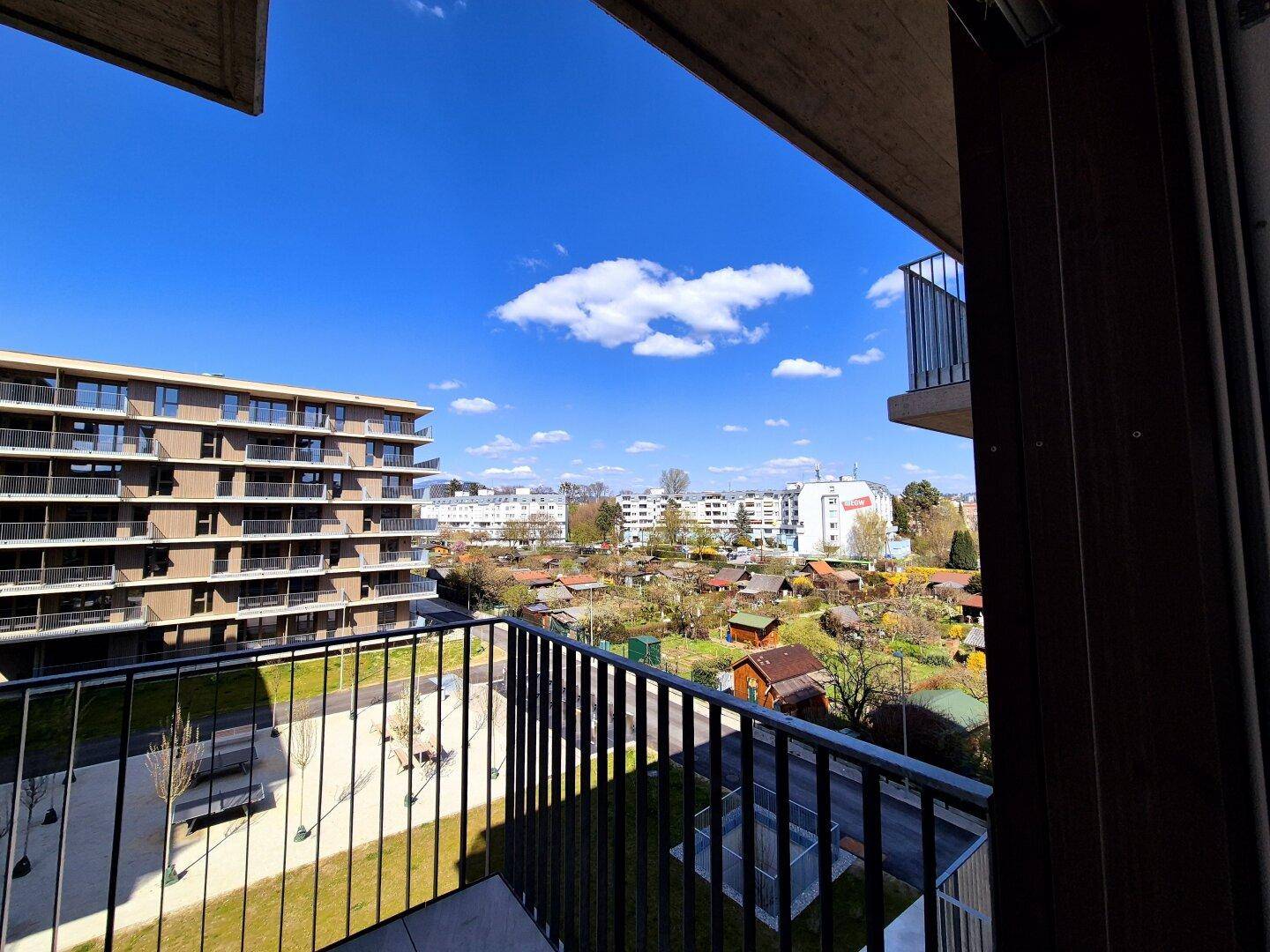 Balkon mit weitem Blick über Kleingärten und die umliegende Wohnbebauung.