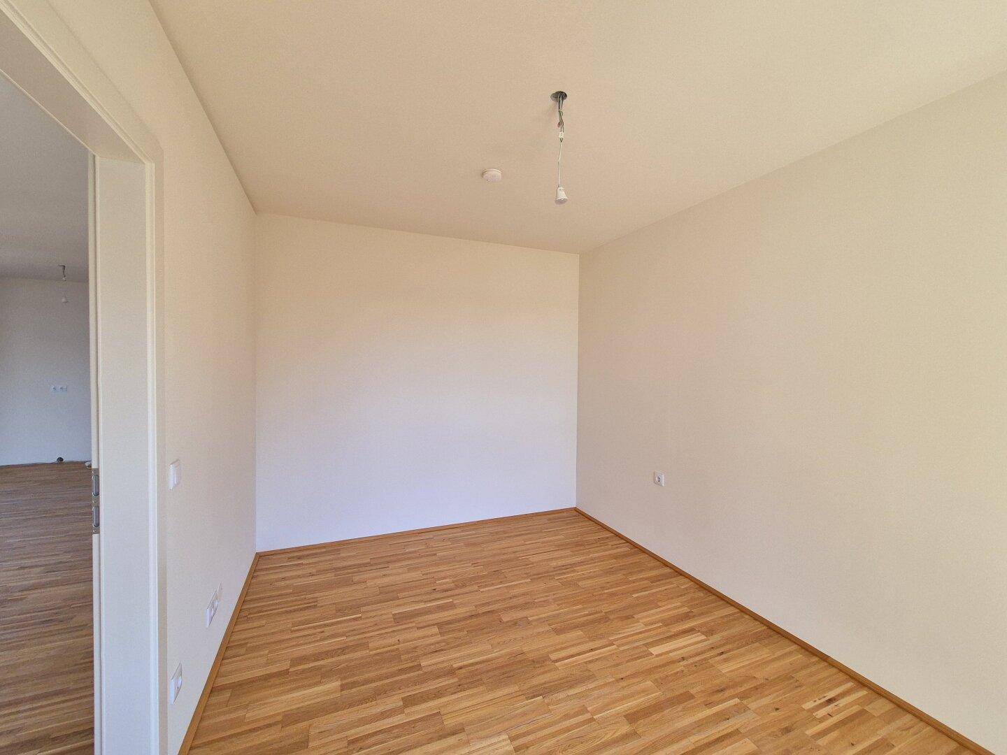 Helles Zimmer mit Holzparkettboden und weiß gestrichenen Wänden, vielseitig nutzbar.