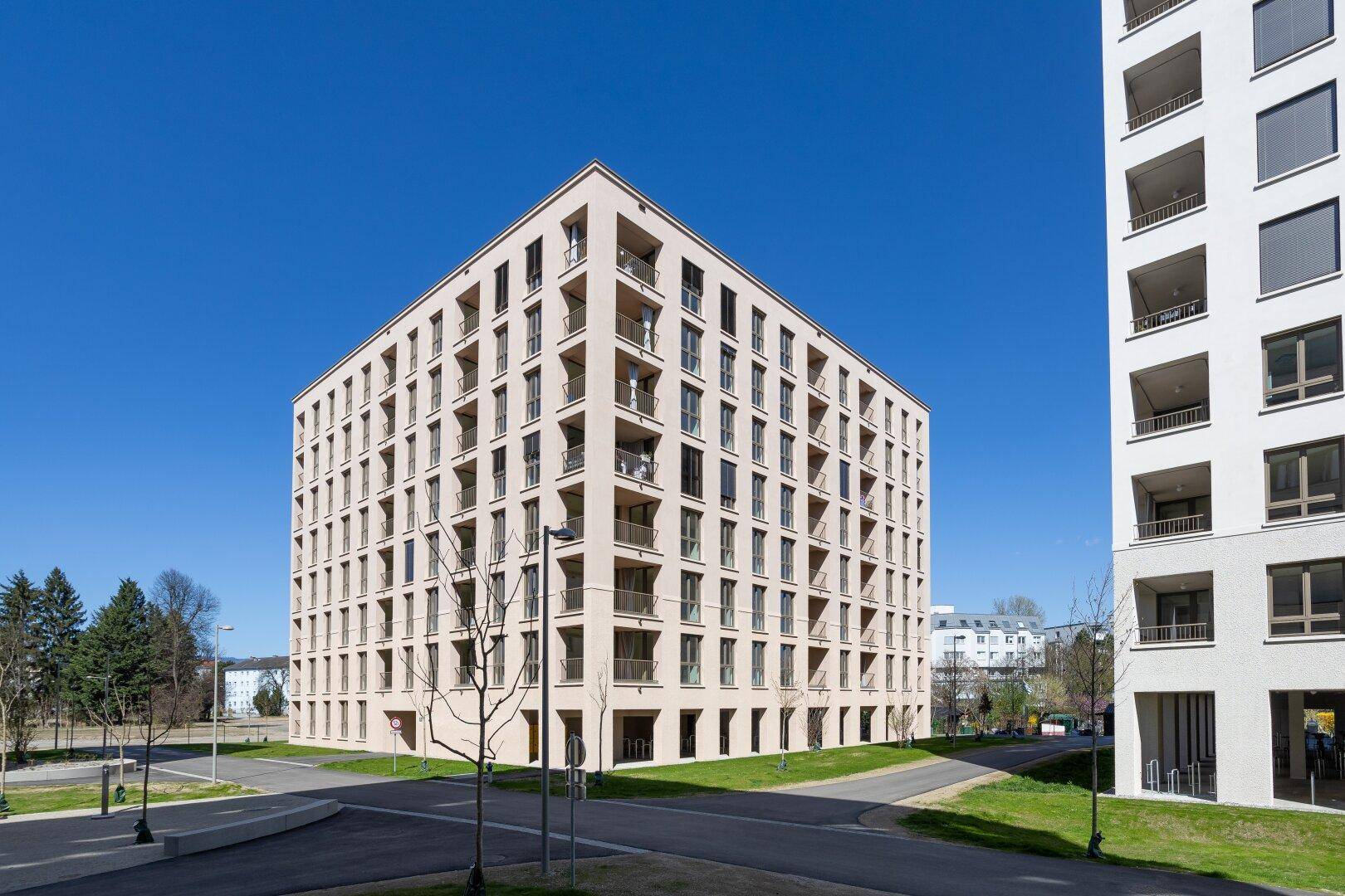 Weitläufige Ansicht eines modernen Wohnkomplexes mit mehreren Gebäuden und Balkonen unter blauem Himmel.