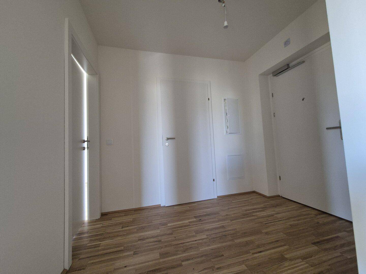 Heller Flur mit Parkettboden und mehreren weißen Türen, die zu den angrenzenden Räumen führen.