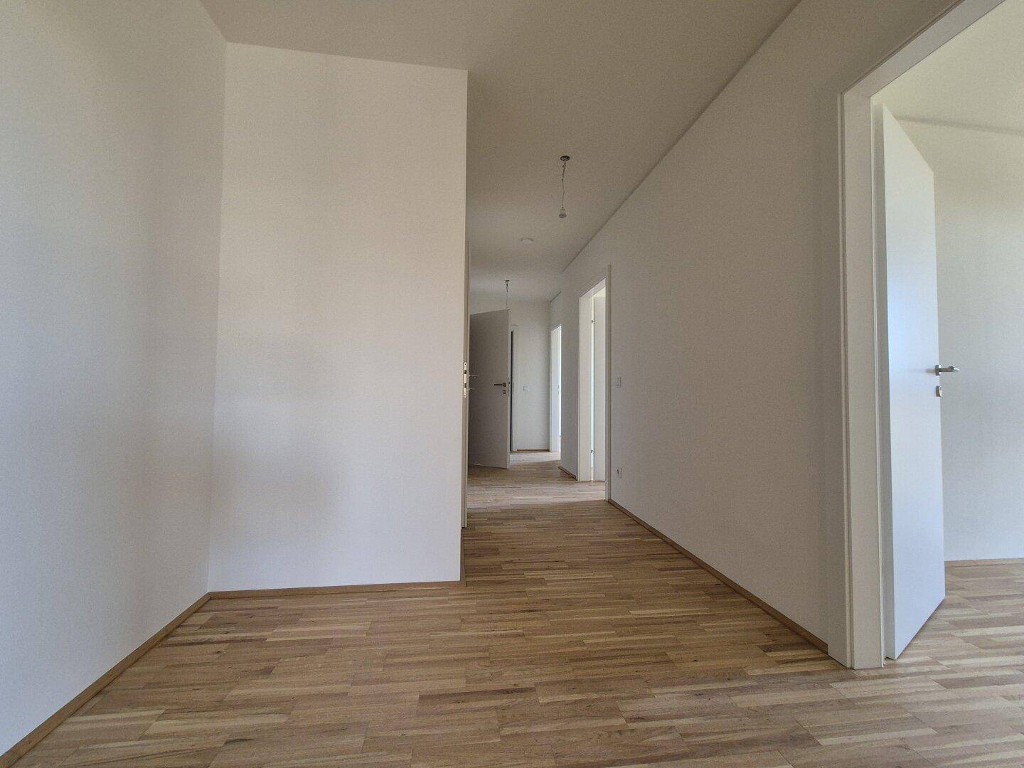 Langer, heller Flur mit Holzparkettboden und mehreren Türen zu den angrenzenden Räumen.