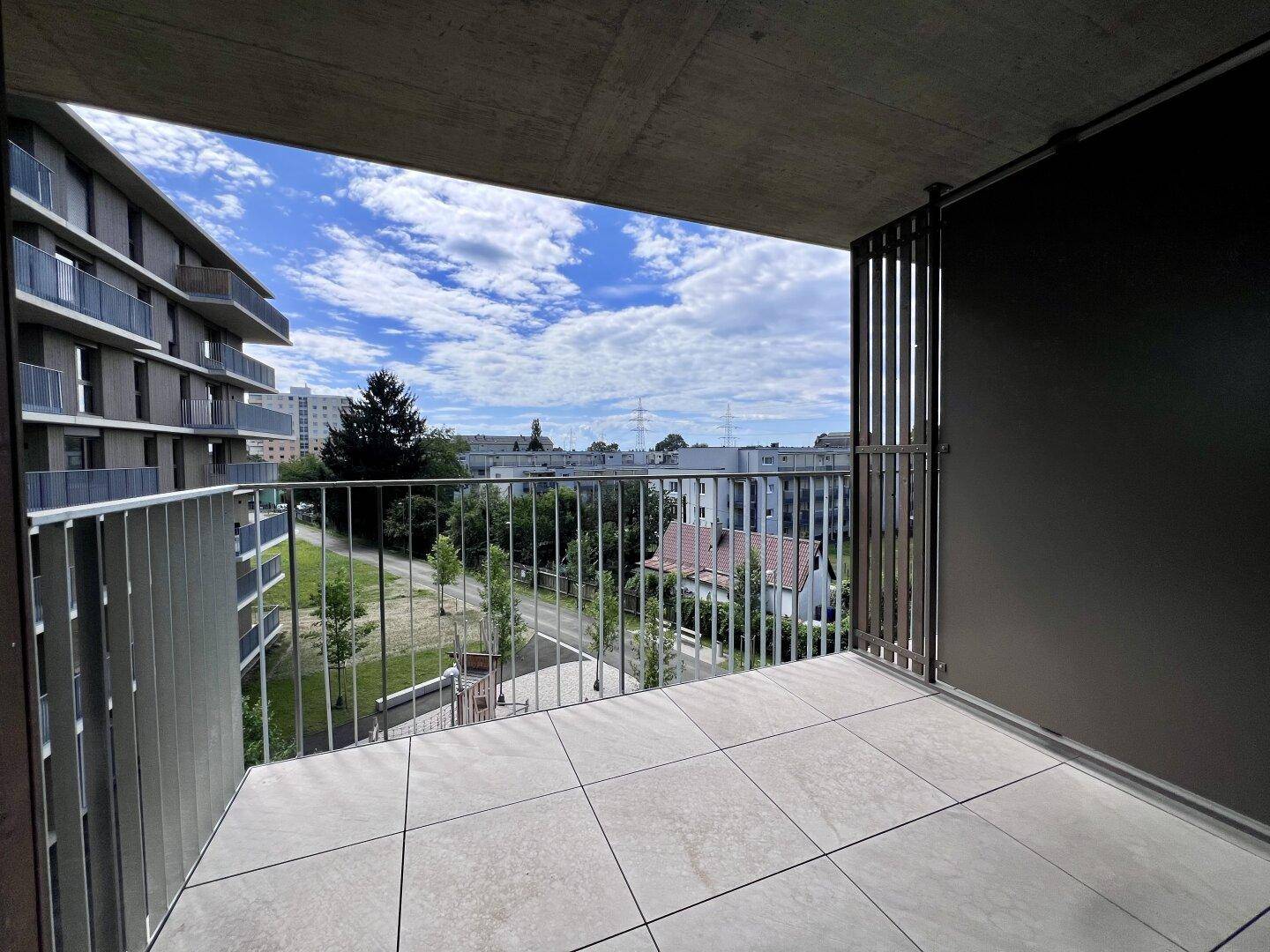 Geräumiger Balkon mit Fliesenboden und Metallgeländer, bietet einen weiten Blick auf die Umgebung.