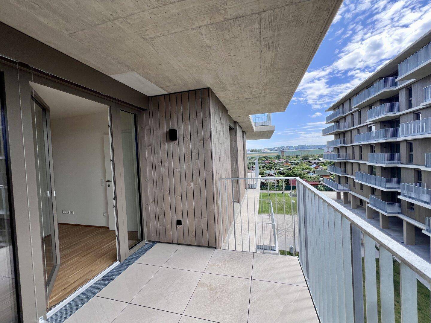 Großer Balkon mit Fliesenboden und Holzverkleidung, bietet einen weiten Blick auf die Umgebung.