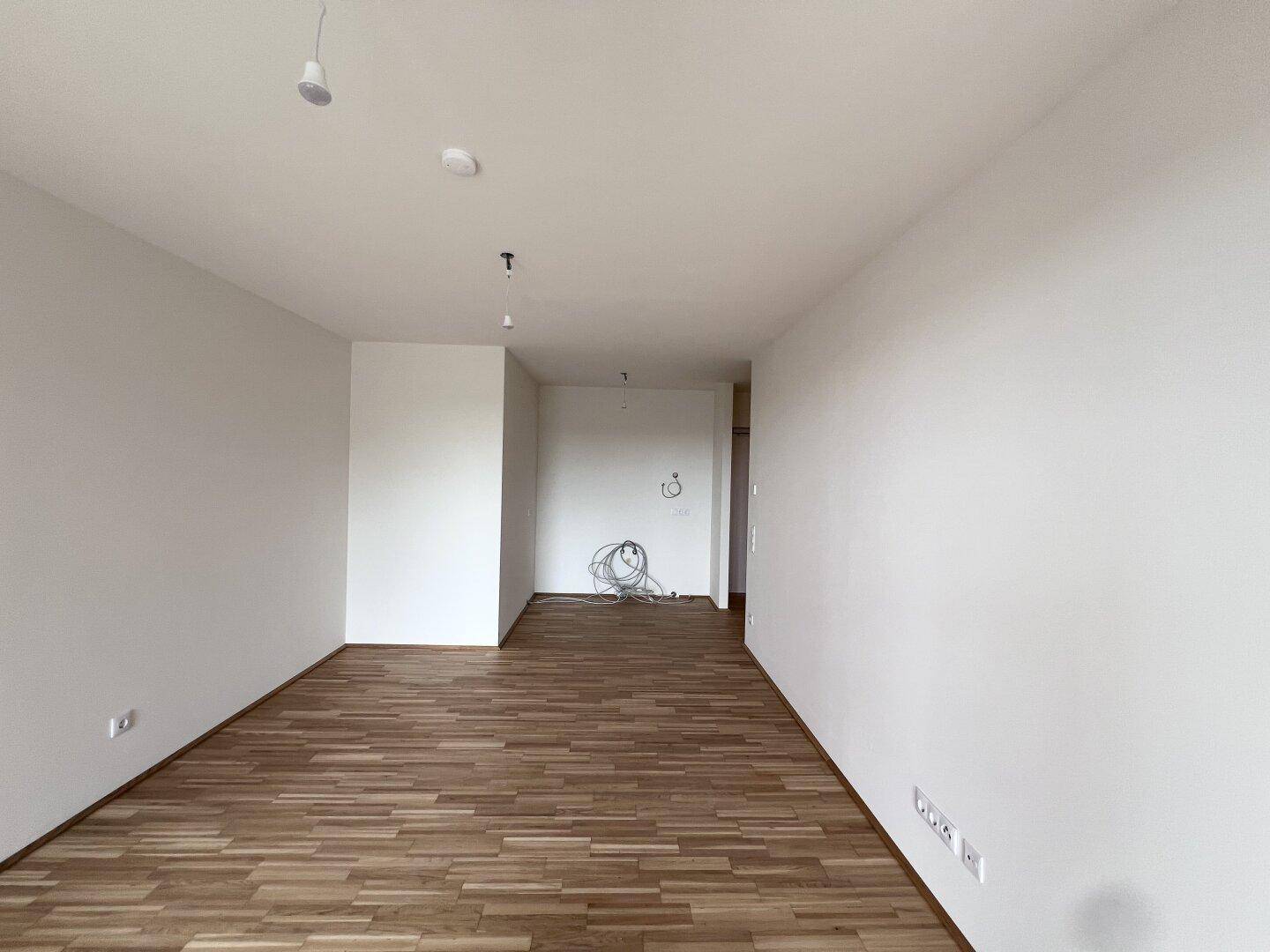 Unmöblierter Raum mit Parkettboden und weißen Wänden, vorbereitet für weitere Installationen.