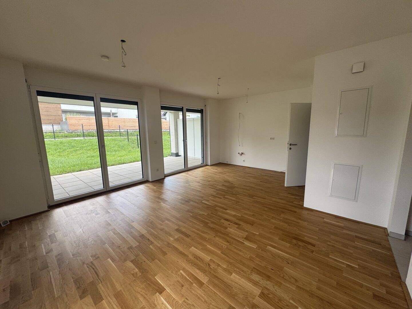 Helles Wohnzimmer mit Holzboden und Zugang zur Terrasse und zum Garten.