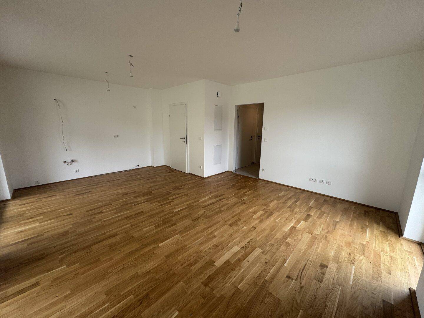 Heller, leerer Raum mit Holzboden und weißen Wänden, bereit für die individuelle Gestaltung.