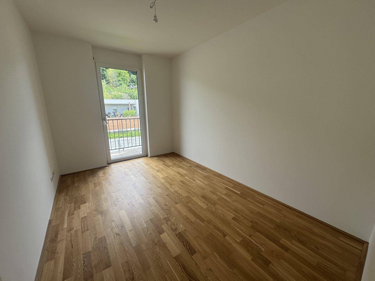 Helles Schlafzimmer mit Holzboden und Zugang zu einem französischen Balkon.