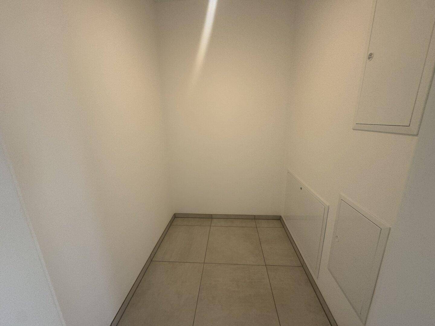 Praktischer Abstellraum mit Fliesenboden und weißen Wänden, ideal für zusätzlichen Stauraum.