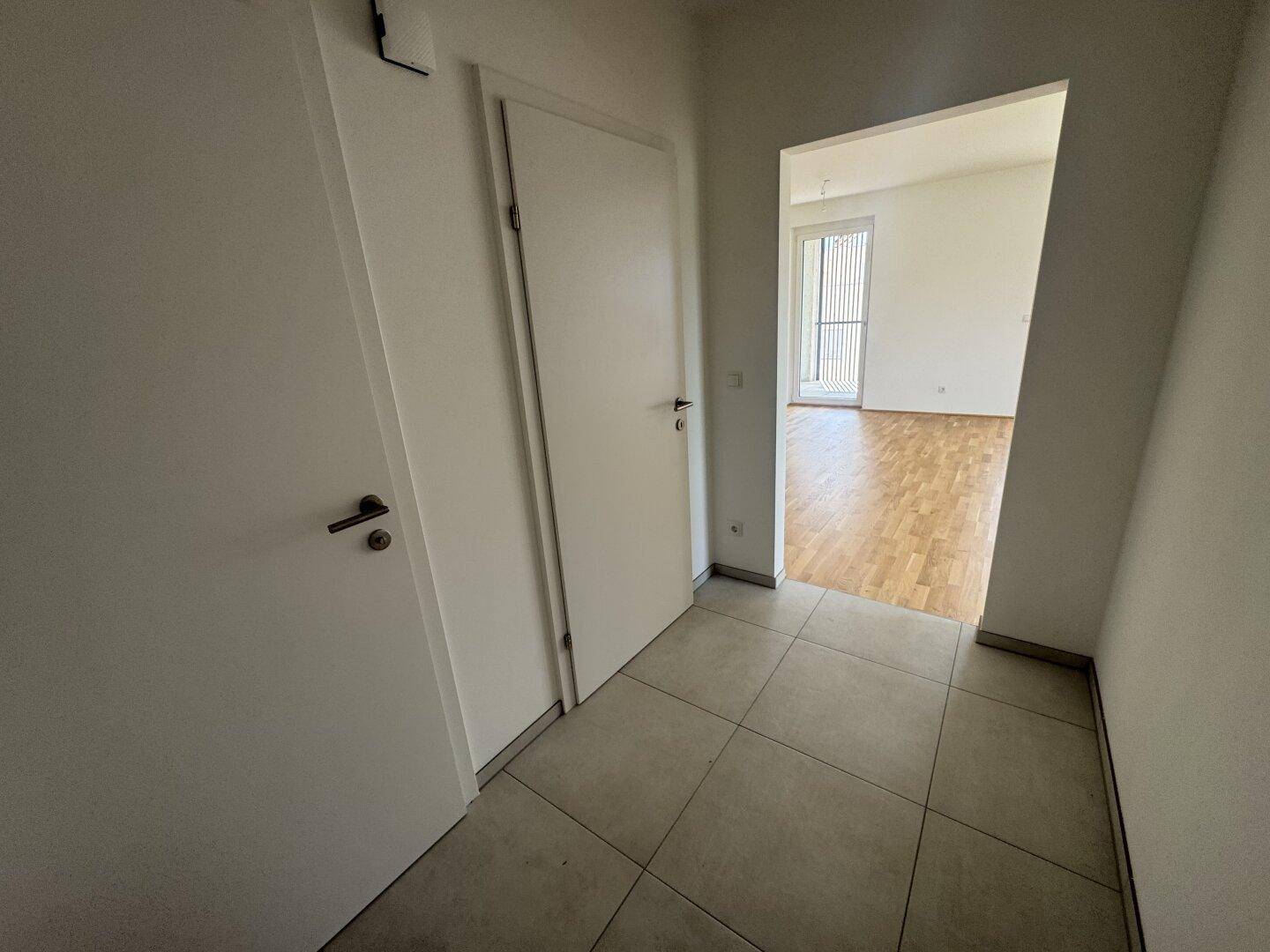 Heller Flur mit Fliesenboden und Zugang zu verschiedenen Räumen der Wohnung.