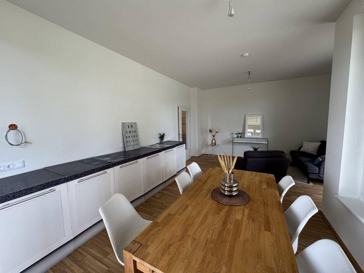 Essbereich mit Holztisch und moderner Küchenzeile, die sich harmonisch in den Wohnraum einfügt.