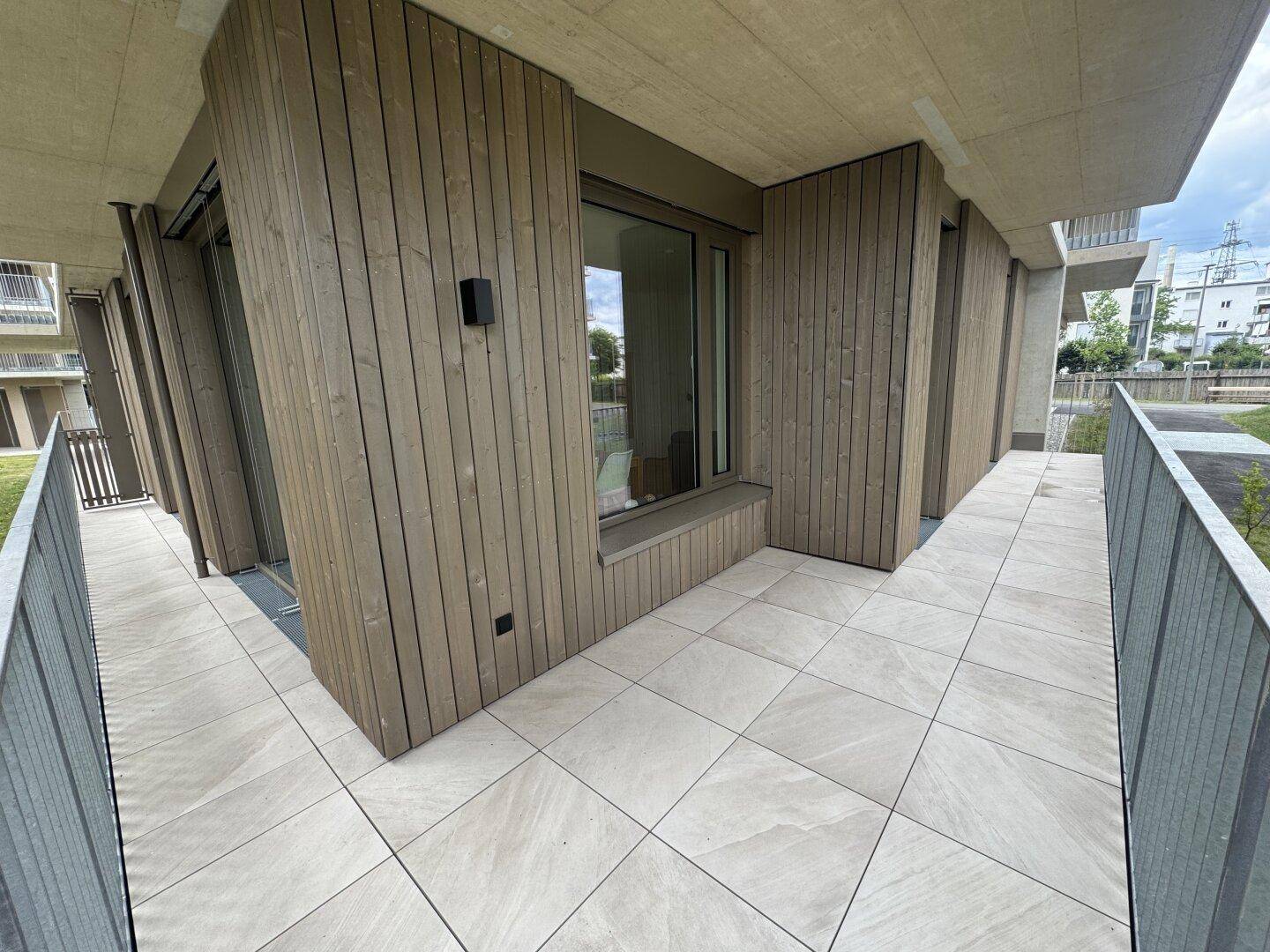Geräumige Terrasse mit modernen Fliesen und Holzverkleidung, ideal für entspannte Stunden im Freien.
