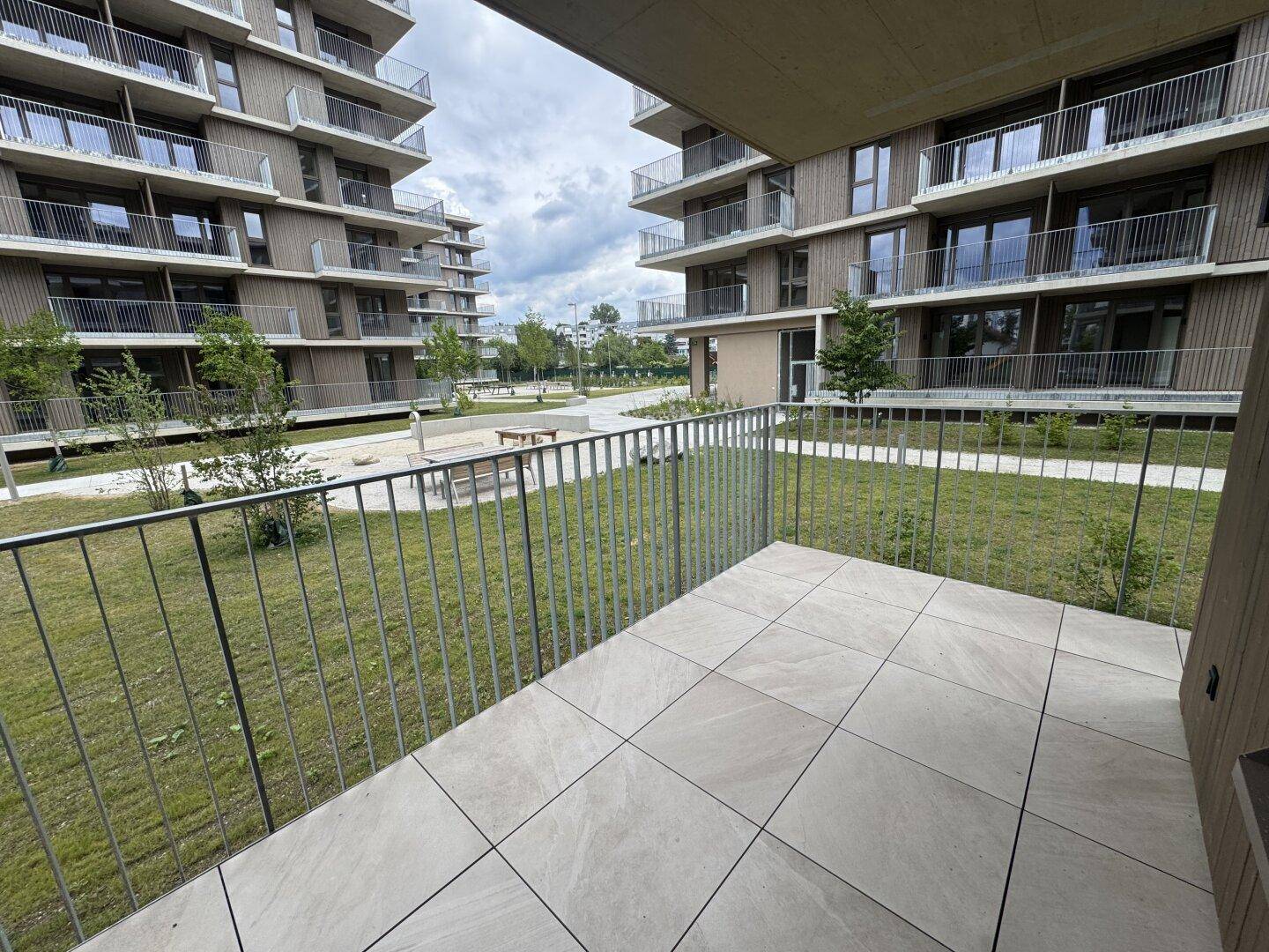 Balkon mit Blick auf die grüne Außenanlage und die moderne Architektur der Wohnanlage.