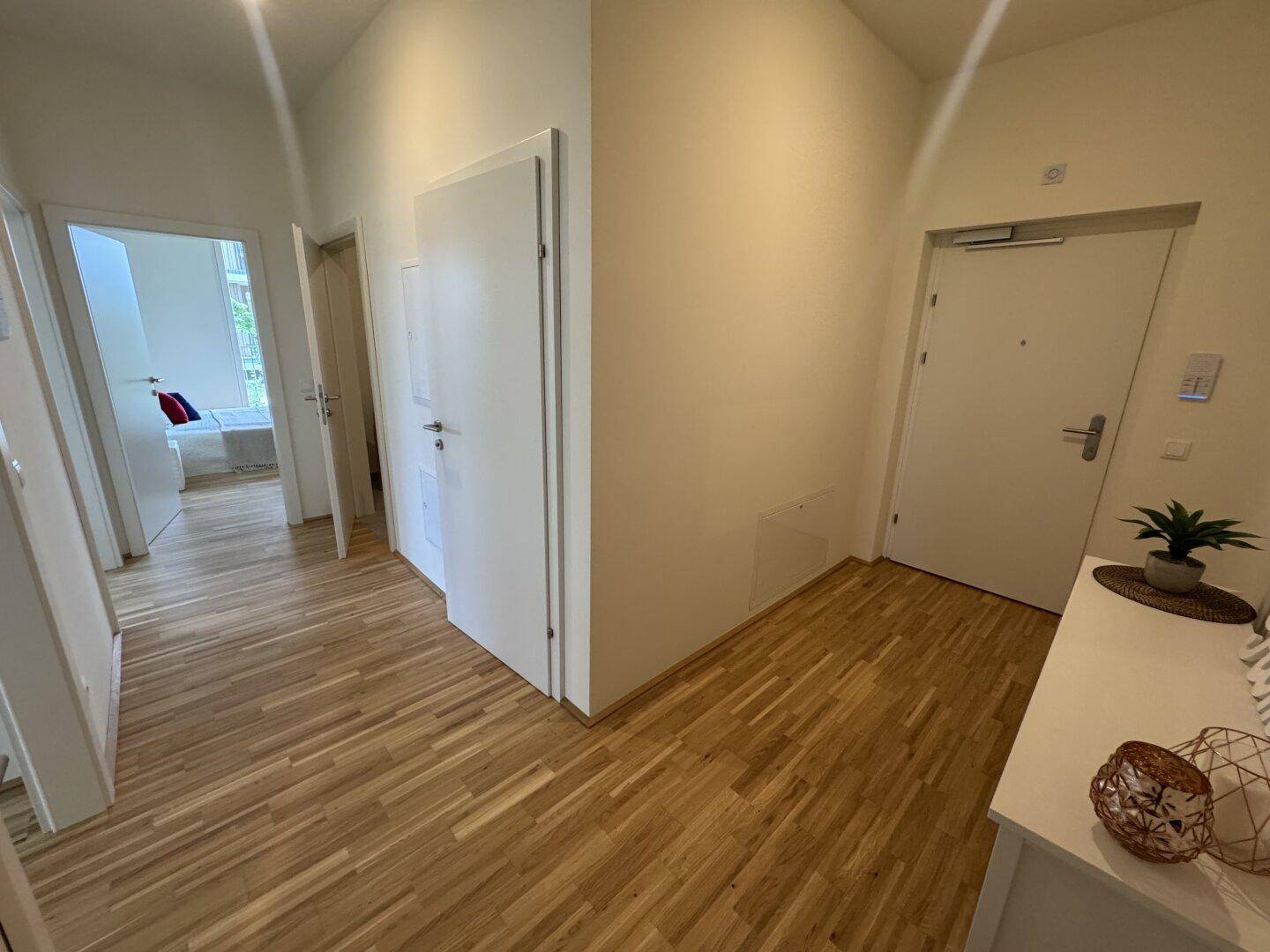 Heller Flur mit modernem Parkettboden, der zu den verschiedenen Räumen der Wohnung führt.