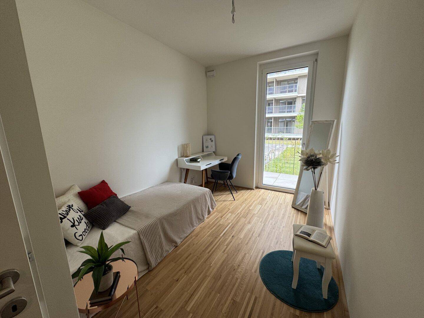 Gemütliches Schlafzimmer mit Holzboden, Schreibtisch und Zugang zum Außenbereich, ideal für Gäste oder Kinder.