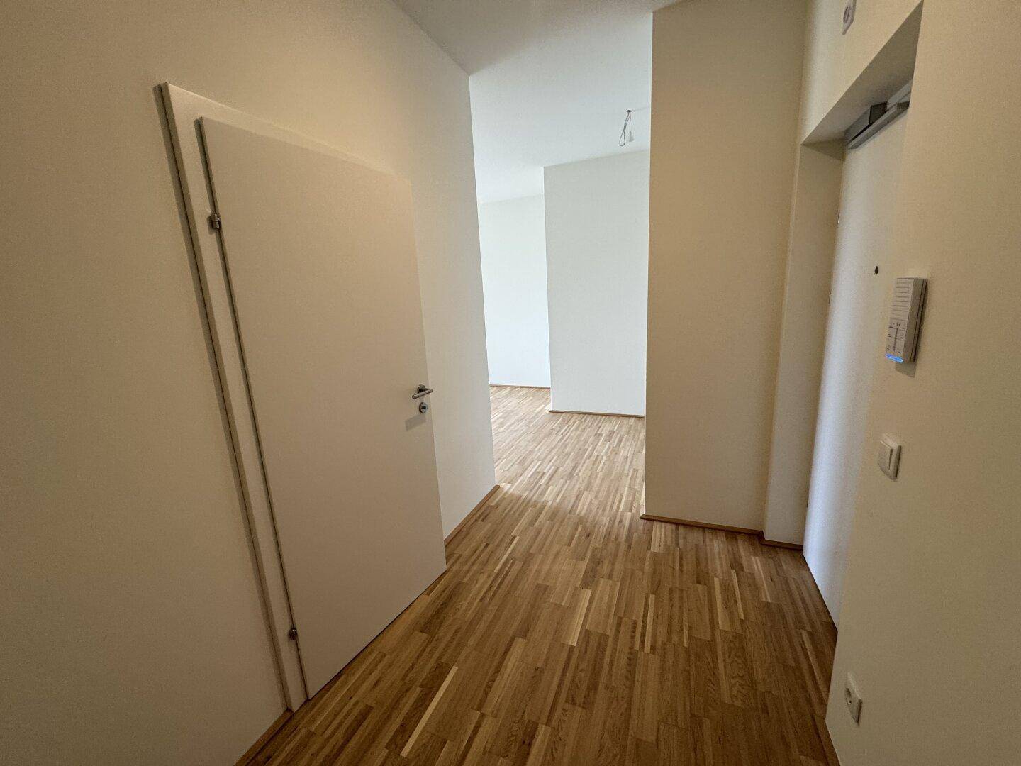 Heller Flur mit Parkettboden und weißen Wänden, ausgestattet mit einer Gegensprechanlage.