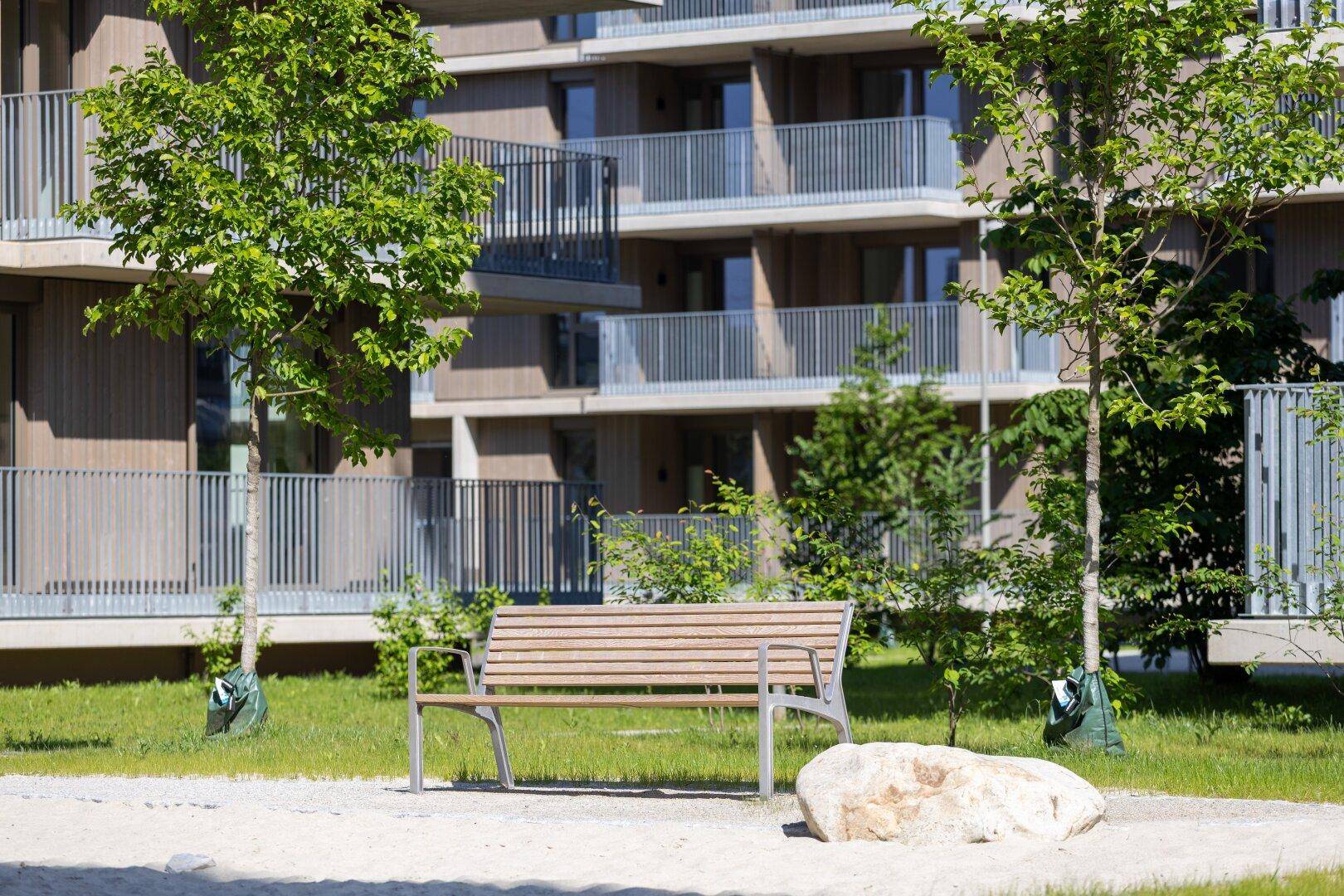 Ruhiger Gartenbereich mit Sitzbank und Kiesfläche, umgeben von Grün, ideal zum Entspannen.