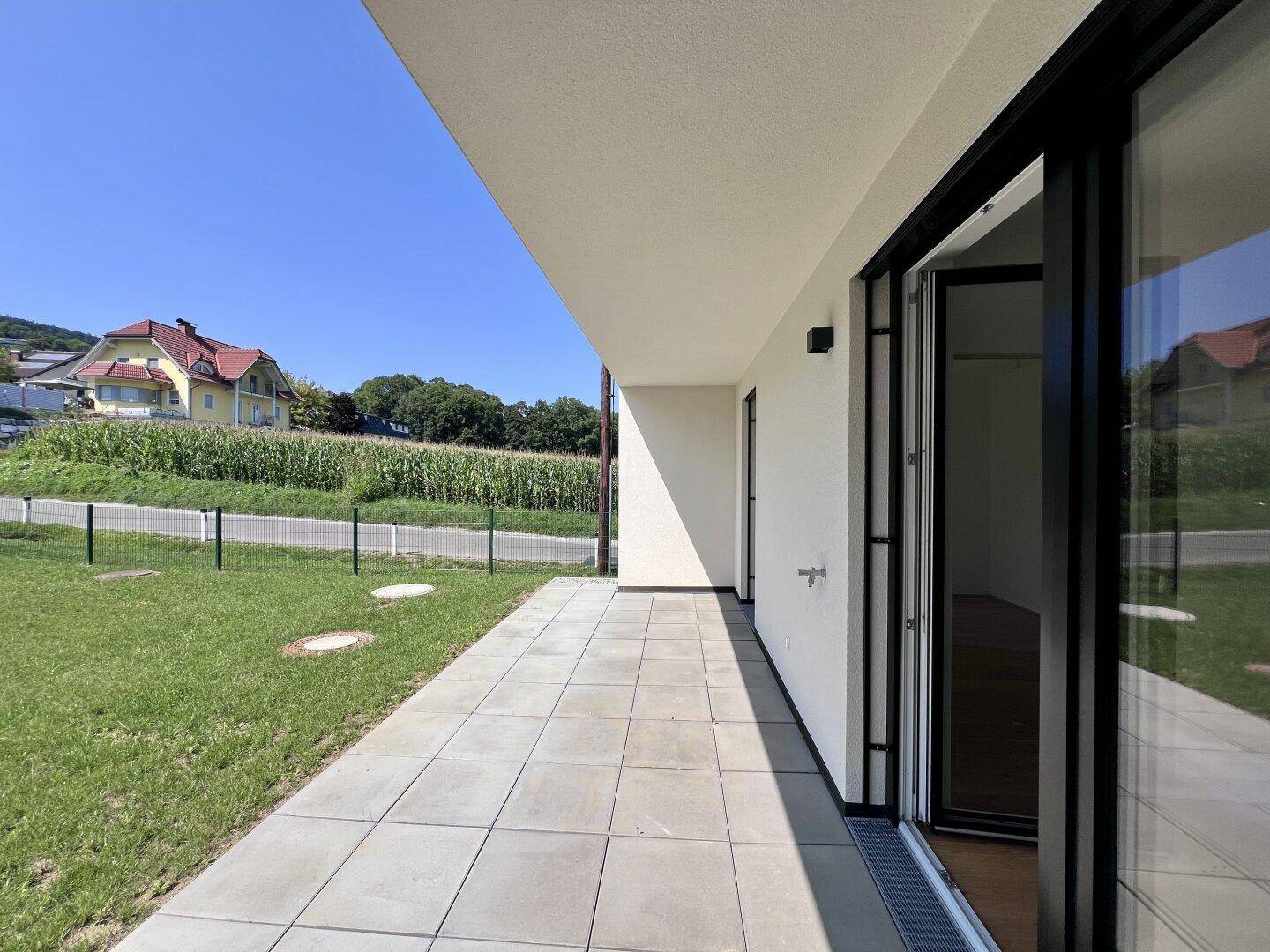 Helle, geräumige Terrasse mit modernen Bodenfliesen und weitem Blick ins Grüne.