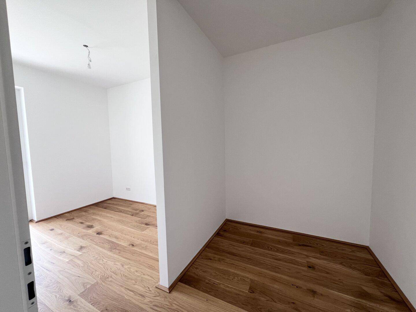 Heller Innenraum mit neuem Holzparkettboden und weißen Wänden, bereit für die Einrichtung.