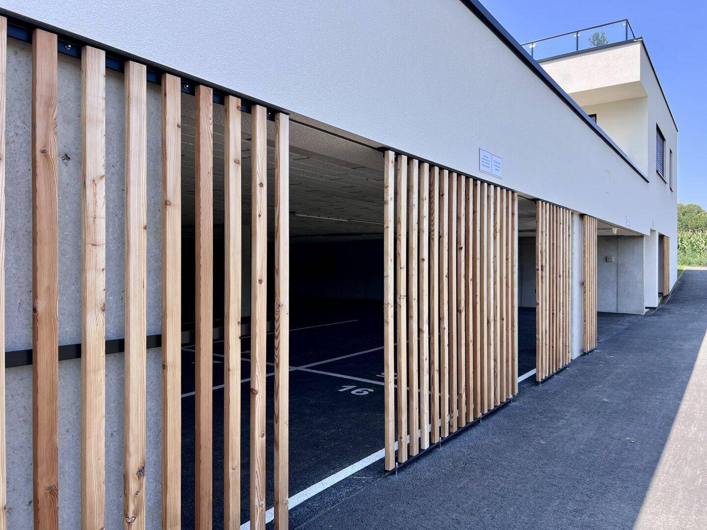Moderner Eingangsbereich zur Tiefgarage mit vertikalen Holzlamellen als Fassadenelement.
