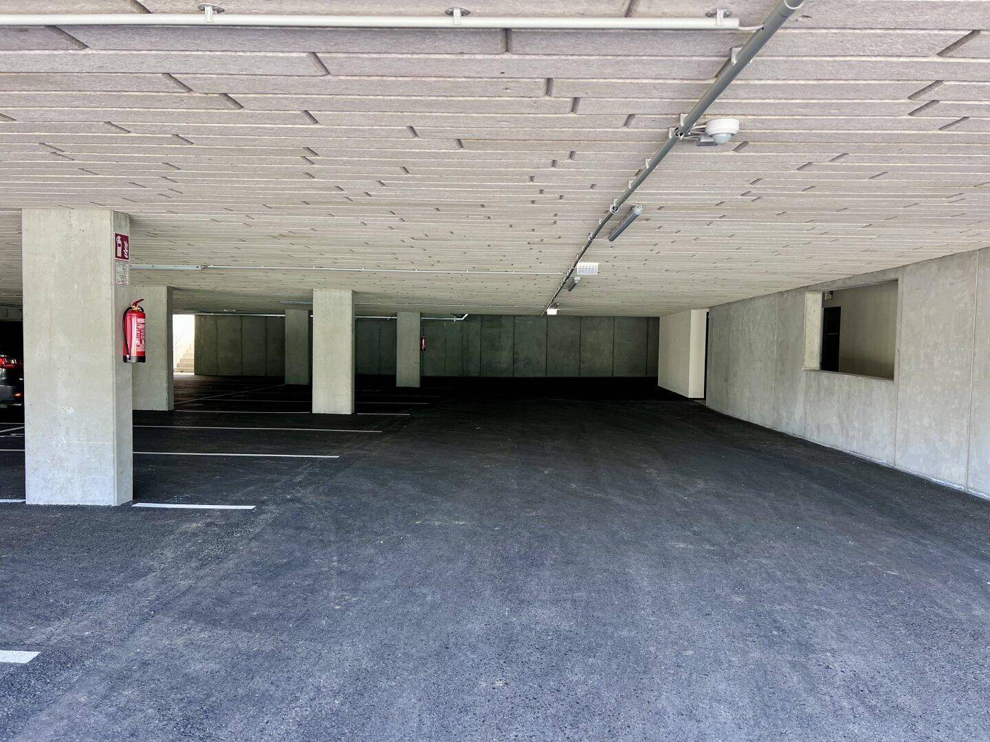 Geräumige Tiefgarage mit markierten Stellplätzen und Brandschutzvorrichtungen.